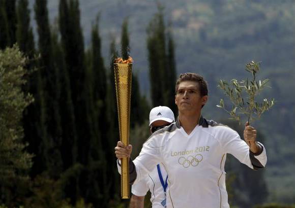 Foto Reuters - Spyridon Gianniotis, campe&#243;n de Grecia en nataci&#243;n, porta la Antorcha ol&#237;mpica y una rama de olivo durante el relevo en la antigua Olimpia en Grecia.