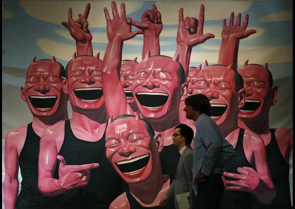 AP - Dos hombres caminan cerca a la obra del artista chino Yue Minjun llamada Entre el hombre y el animal durante el avance para la prensa de la subasta del artista en Hong Kong.