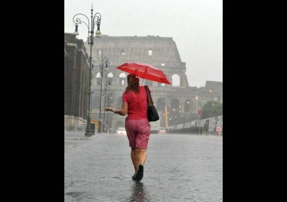 AP - Una mujer camina hacia el coliseo romano en un d&#237;a particular de lluvia en el verano de Roma.