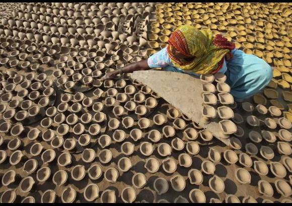 Reuters - Una mujer saca lámparas de barro al sol para que se sequen en su taller antes de la fiesta hindú de Diwali en la norteña ciudad india de Chandigarh.