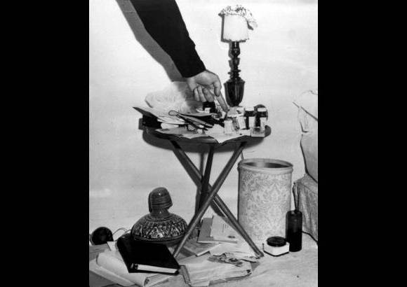 AP - El 5 de agosto 1962, un oficial de polic&#237;a muestra los frascos de medicina al lado de la cama de la actriz Marilyn Monroe, en Los &#193;ngeles, California, donde fue encontrada muerta.