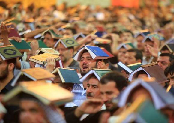 Reuters - Musulmanes chi&#237;tas usan una copia del Cor&#225;n en la cabeza durante una ceremonia para conmemorar el aniversario de la muerte del Imam Ali en su santuario en la ciudad santa de Najaf, a unos 160 kil&#243;metros al sur de Bagdad, Irak.