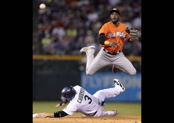 AP - El jugador de los Marlins de Florida Adeiny Echavarría, arriba, salta por encima del jugador de los Rockies de Colorado Michael Cuddyer (3) en la segunda base y observa su tiro a la primera en el sexto inning de un partido de béisbol en Denver, Estados Unidos.