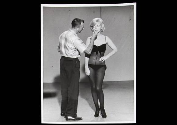 AP - Una imagen muestra a Snyder maquillando a la legendaria actriz, ataviada en lencer&#237;a, en el set de La adorable pecadora (Let&#39;s Make Love) en 1960.