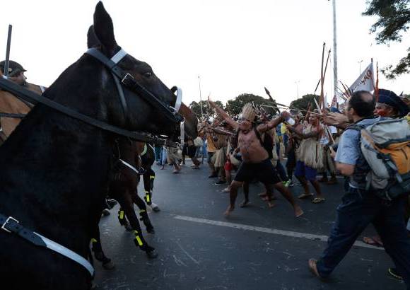 AP - Los manifestantes ind&#237;genas se enfrentaron con la polic&#237;a montada brasile&#241;a en la capital del pa&#237;s, afuera de un nuevo estadio de f&#250;tbol que ser&#225; sede de la Copa del Mundo.