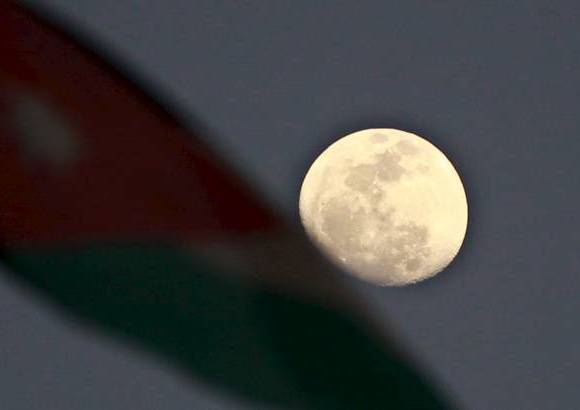 Reuters - Esta imagen es en Ammán, Jordania. Una bandera Nacional Jordana se representa junto a la luna durante una manifestación contra el gobierno organizada por los manifestantes conocidos como "Los jóvenes del Movimiento del 24 de marzo".