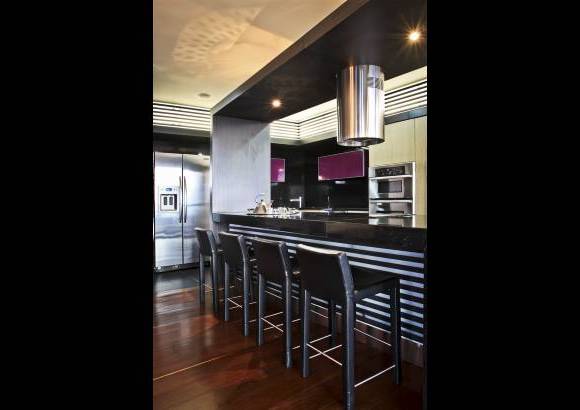 Foto Juan Fernando Cano - En la cocina, en el mueble de fondo y debajo de la barra, está presente el lenguaje de líneas horizontales de las persianas de madera.
