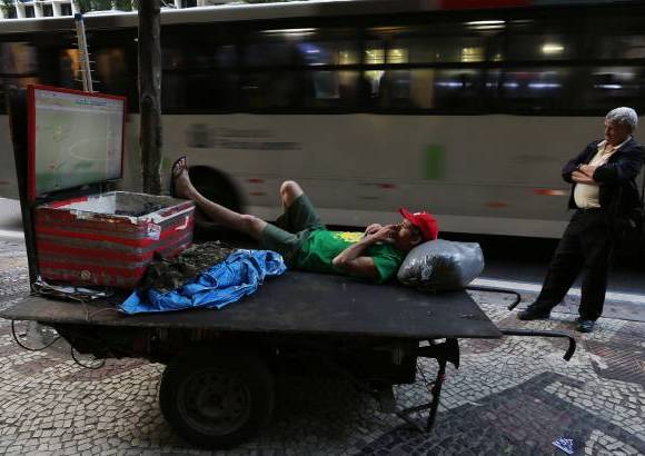 AP - En una acera del centro de Río de Janeiro, Elias Vieira, de 40 años, observa el partido de fútbol amistoso entre Brasil y Panamá, en un televisor de pantalla plana instalado en su carreta de trabajo.