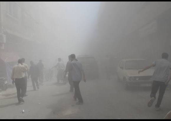 Reuters - Residentes del barrio Duma de Damasco caminan frente al humo despu&#233;s que activistas dijeran que era un ataque a&#233;reo de las fuerzas leales al presidente de Siria Bashar al-Assad