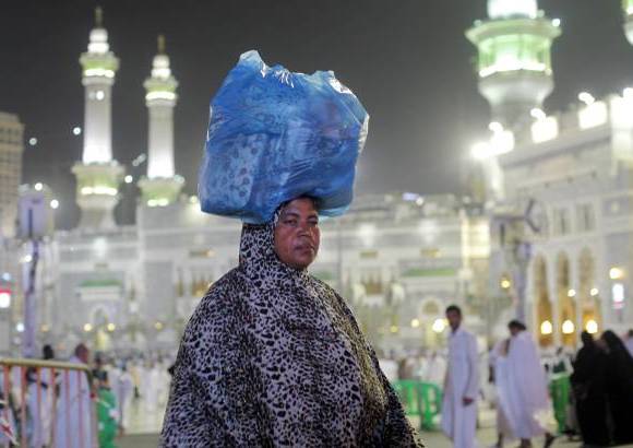 AP - Una peregrina musulm&#225;n lleva su equipaje frente a la Gran Mezquita de la ciudad santa de La Meca, Arabia.