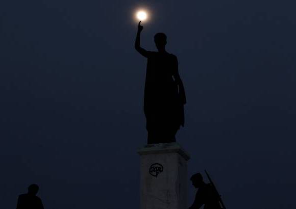 AP - Esta imagen es en Nicosia, Chipre. La Luna se levanta detrás de una estatua que representa la libertad de Chipre.