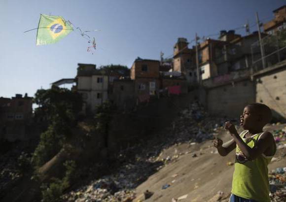 AP - En las laderas del barrio de Mangueira, un niño vuela una cometa.