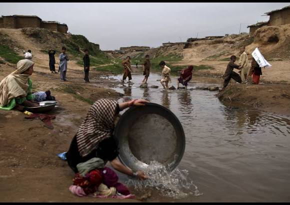 AP - Niñas pakistaníes lavan su ropa en un arroyo contaminado en un barrio pobre en las afueras de Islamabad, Pakistán.