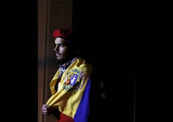Reuters - Un partidario del presidente de Venezuela, Hugo Ch&#225;vez en M&#233;xico aguard&#243; en las afueras de la embajada de Venezuela en la Ciudad de M&#233;xico envuelto en una bandera venezolana.