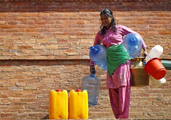 AP - Una mujer nepalí espera para llenar sus recipientes con agua cerca de Patan, en Nepal.