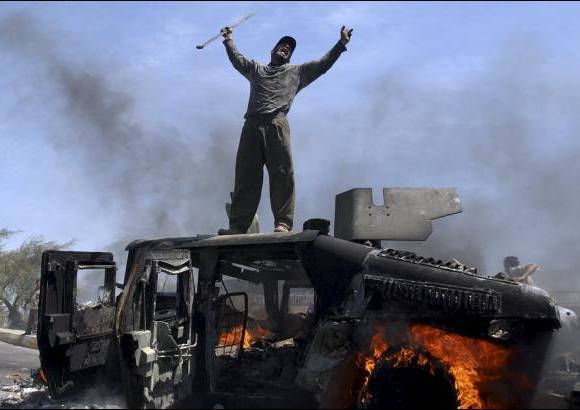 AP - Un hombre iraqu&#237; celebra sobre el veh&#237;culo quemado del ej&#233;rcito de Estados Unidos el 26 de abril de 2004.