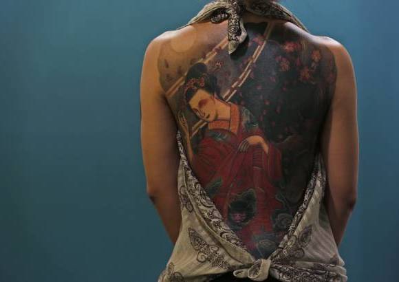AP - Una mujer muestra su tatuaje durante la primera convenci&#243;n internacional de tatuaje en China.