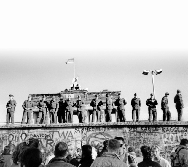Soldados fronterizos del Este sobre una parte del Muro de Berlín con la Puerta de Brandenburgo de fondo. FOTO AFP