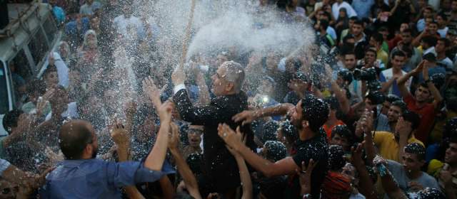 El portavoz de Hamas, Fawzi Barhoum, (centro) fue alzado en hombros por palestinos que celebran la tregua definitiva, que consideran como una victoria sobre Israel. FOTO REUTERS