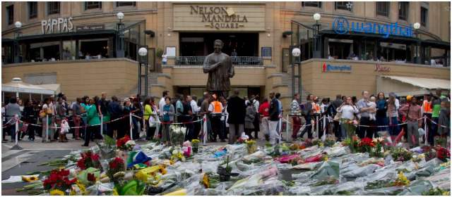 Ofrendas florales se acumulan a los pies de una estatua del ex presidente Nelson Mandela, en la plaza que lleva su nombre en Sandton City, en Johannesburgo. FOTO AP