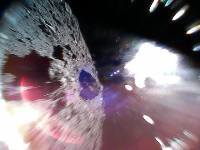 Imagen en color capturada mientras un explorador se mueve (durante un salto) en la superficie de Ryugu. La mitad izquierda de la imagen es la superficie del asteroide. La región blanca brillante es provocada por la luz solar. Foto: JAXA