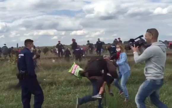 Momento en que la periodista pone zancadilla a un hombre que carga a un niño. FOTO Twitter