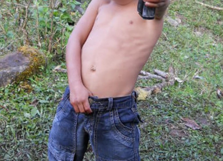 Un menor de cinco años toma una pistola, al parecer, en uno de los campamentos de la guerrilla en Cauca. FOTO cortesía ejército