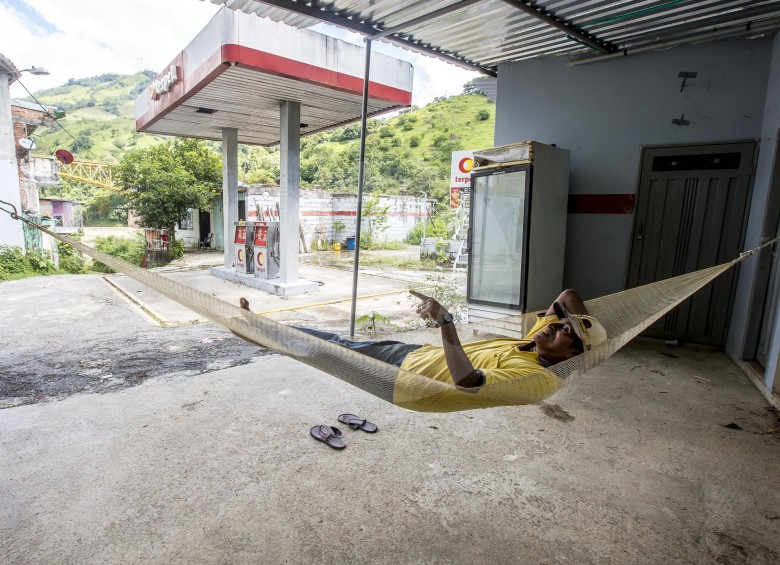 Un pescador descansa entre los restos de una estación de gasolina abandonada.