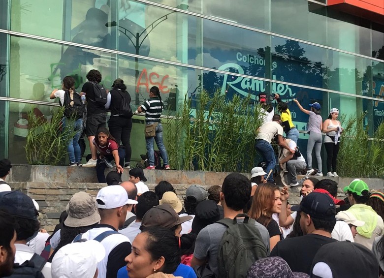 Estudiantes borran grafitis en el centro comercial Premium Plaza y expulsan de la marcha a los que lo rayaron. FOTO JULIO CÉSAR HERRERA