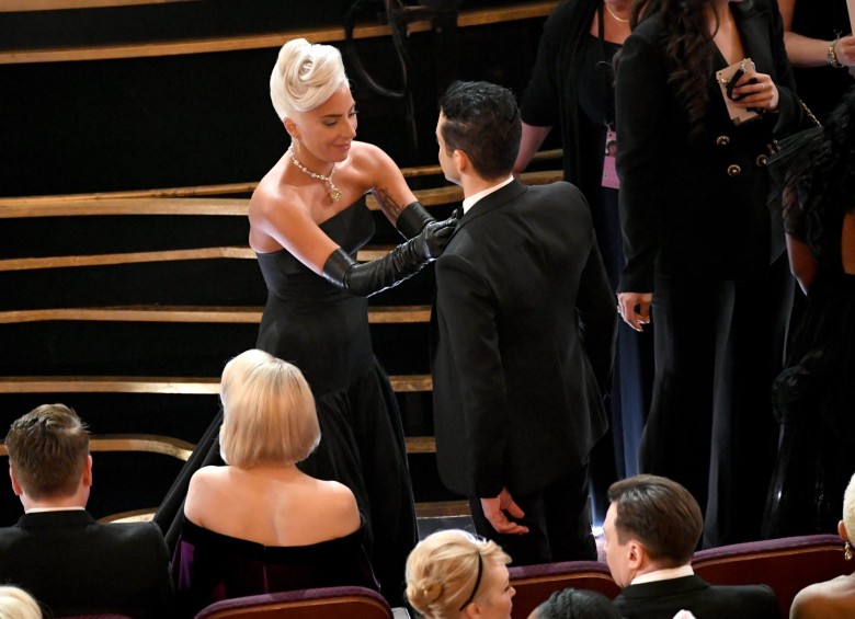 Lady Gaga le acomoda el corbatín a Rami Malek en los comerciales. FOTO AFP