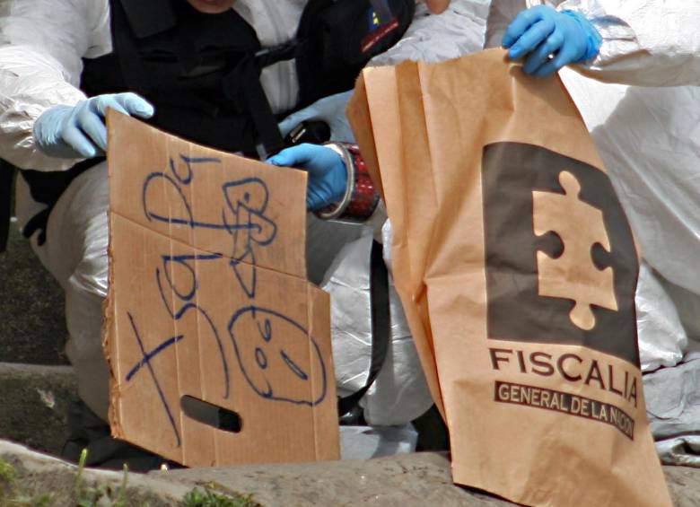 Esta imagen corresponde a un homicidio del 16 de junio de 2011, cuando una despachadora de buses fue asesinada a bala en una calle de la comuna 13. Los agresores dejaron ese mensaje en un pedazo de cartón, junto a la víctima. FOTO: Archivo.