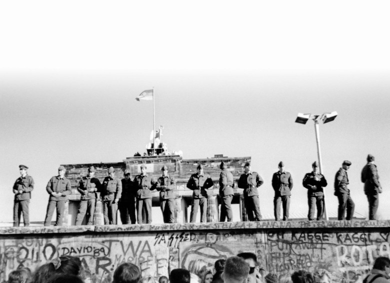 Soldados fronterizos del Este sobre una parte del Muro de Berlín con la Puerta de Brandenburgo de fondo. FOTO AFP