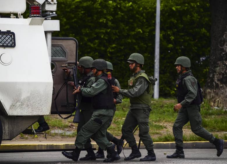 Integrantes de la Guardia Nacional Bolivariana ingresan a un vehículo blindado en medio del enfrentamiento armado que causó un grupo de militares y civiles que entraron al fuerte de Paramacay en la ciudad de Valencia.