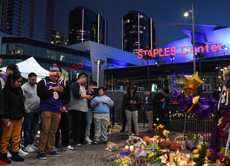 Fanáticos se reúnen cerca de un monumento improvisado mientras lloran la muerte de la leyenda de la NBA, Kobe Bryant, quien murió junto con su hija y otras siete personas en un accidente de helicóptero el 26 de enero, en la plaza LA Live frente al Staples Center. Foto: AFP. 