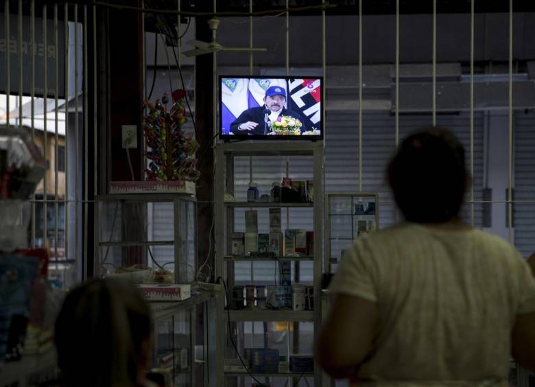 Dos mujeres observan en la pantalla de un televisor, en una tienda de abarrotes, al presidente de Nicaragua, Daniel Ortega, durante la transmisión de Cadena Nacional en Managua. FOTO EFE