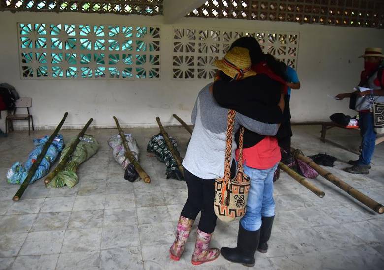Indígenas se abrazan frente a los cadáveres en un salón del resguardo. FOTO EFE