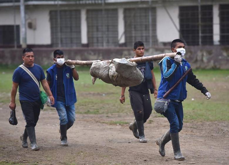 Indígenas transportan los cuerpos para llevarlos al Instituto Nacional de Medicina Legal y Ciencias Forenses en Cali. FOTO EFE