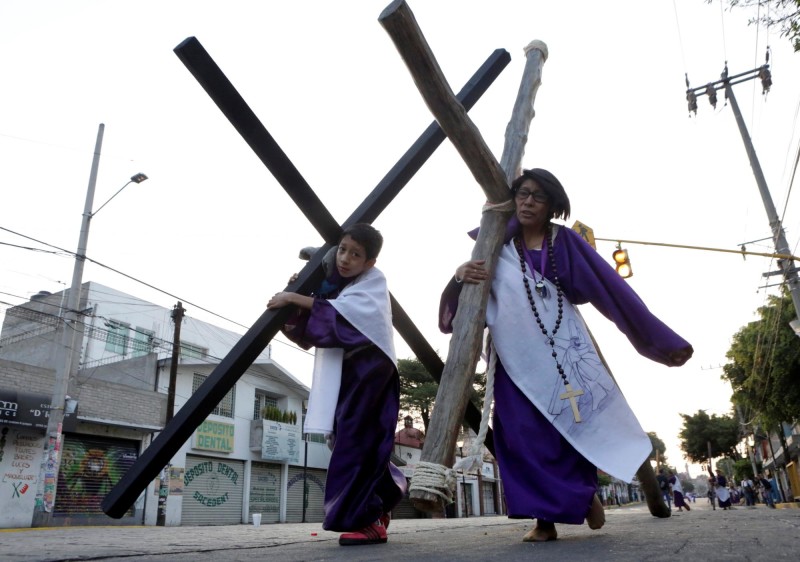 Un niño y una mujer cargan las cruces en Ciudad de México. FOTO REUTERS