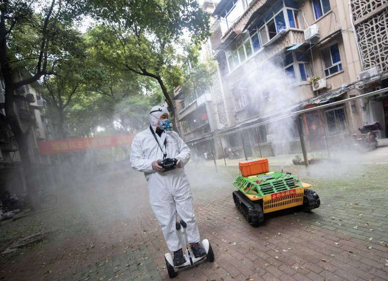 Un voluntario opera un robot de desinfección en Wuhan. FOTO AFP