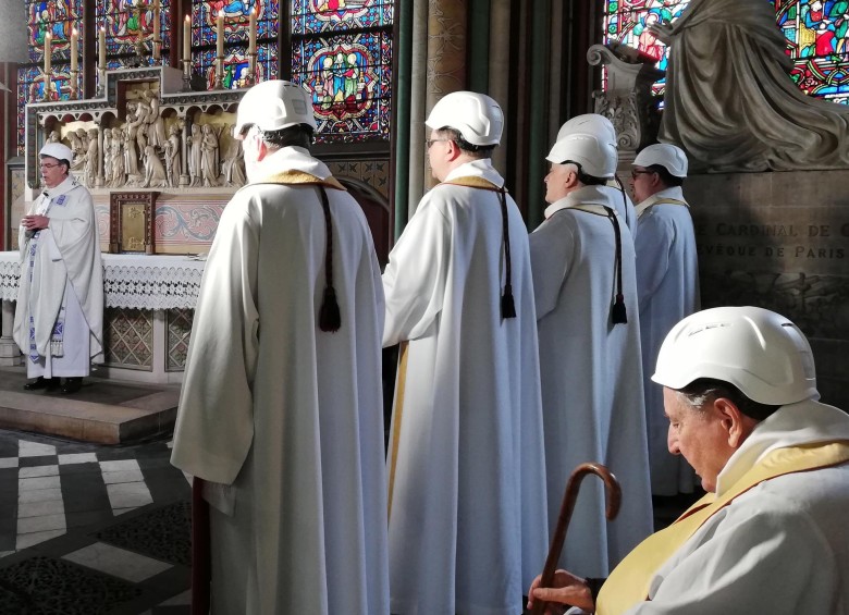 Los asistentes a la primera misa en Notre Dame utilizaron cascos para protegerse. Foto: EFE