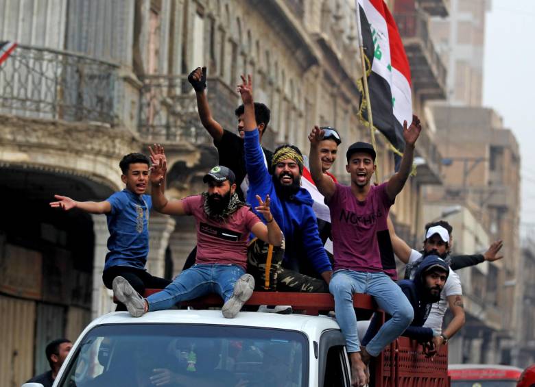Manifestantes en Bagdad celebran con una bandera nacional después de la renuncia del primer ministro, Adel Abdul-Mahdi. FOTO AFP