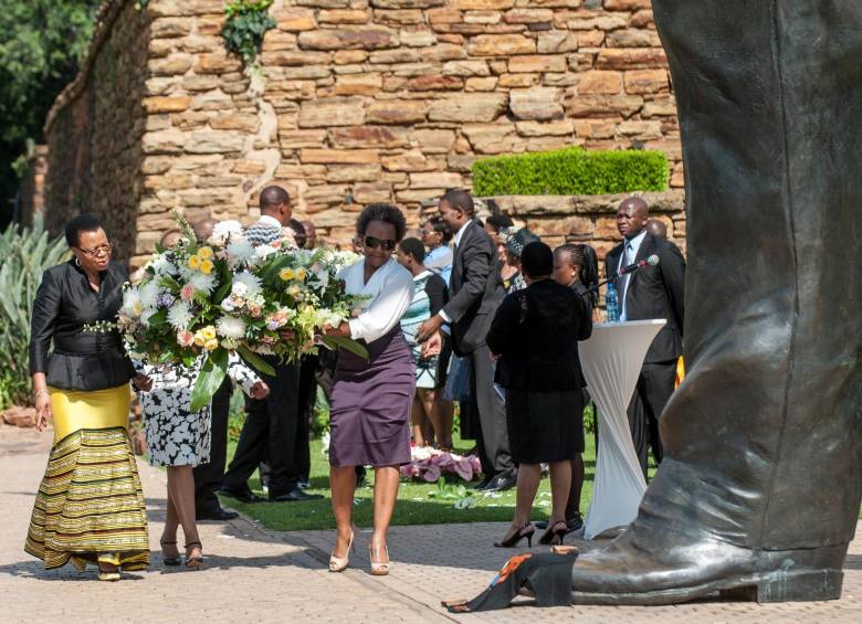 Graça Machel, la vuida de Mandela (izq.) fue temprano a la estatua de bronce de su esposo para llevarle una ofrenda floral y recordarlo en su primer aniversario de muerte.