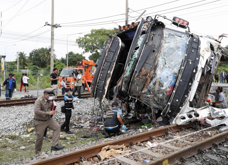 Policías y agentes forenses tailandeses inspeccionan un autobús destrozado después de que chocó con un tren en la estación de tren de Khlong Kwaeng Klan. FOTO EFE
