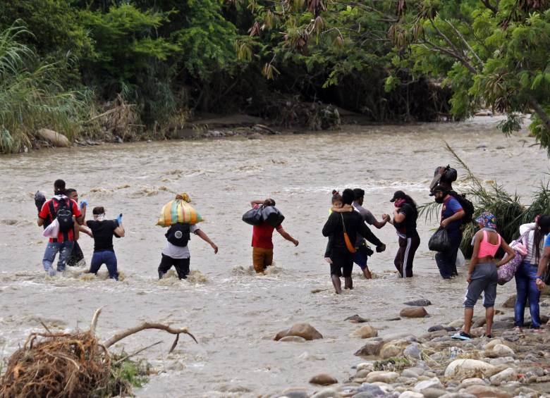 Migrantes venezolanos atraviesan el río para llegar a Colombia. FOTO AFP