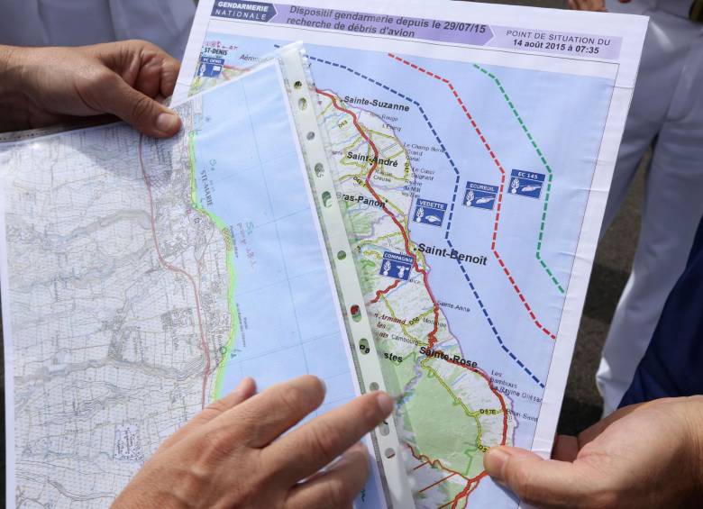Gendarmes marítimos franceses analizan en un mapa la ruta a seguir en busca del fuselaje del avión malasio perdido hace un año en el Océano Índico. AFP-Richard Bouhet