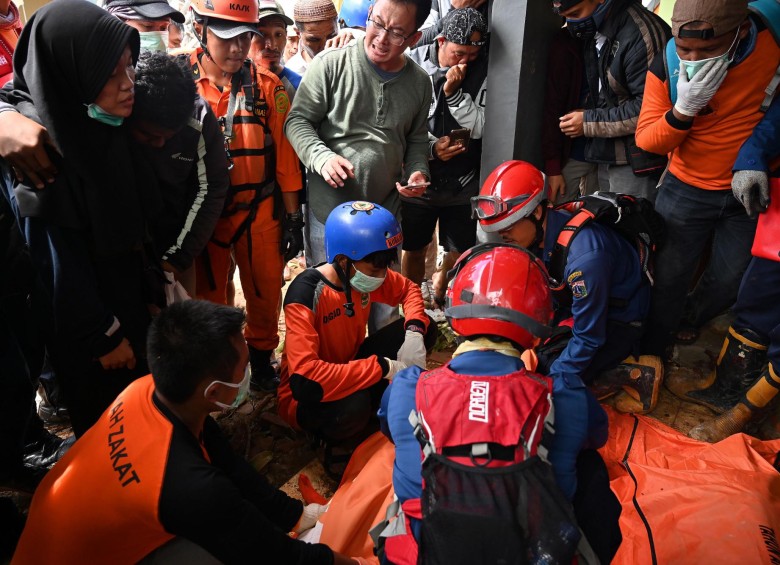 Personas junto a los cadáveres rescatados en Indonesia. FOTO AFP