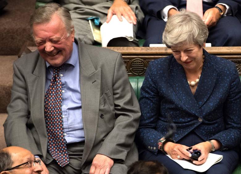 La exprimera ministra, Theresa May, ríe junto al parlamentario conservador Kenneth Clark en medio del debate para frenar a Johnson. FOTO: AFP
