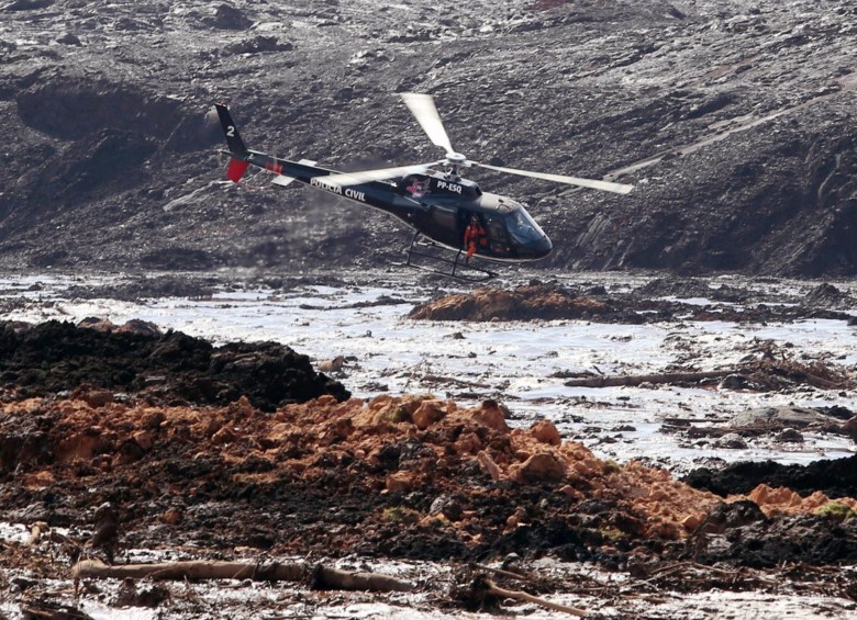 Un helicóptero busca sobrevivientes entre el río de lodo que cayó tras la ruptura de la represa. FOTO EFE