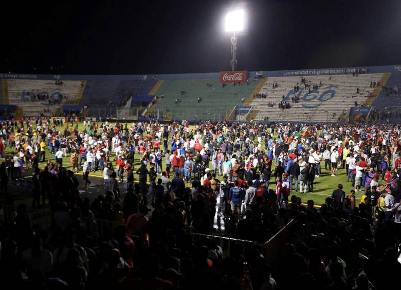 Aficionados ingresan al campo y se protegen de los gases lacrimógenos lanzados por las autoridades, debido a los disturbios a las afueras del Estadio Nacional por la cancelación del clásico entre Olimpia y Motagua hoy sábado, en Tegucigalpa. Al menos tres jugadores resultaron heridos leves este sábado en un ataque al autobús del equipo hondureño Motagua. Foto: EFE