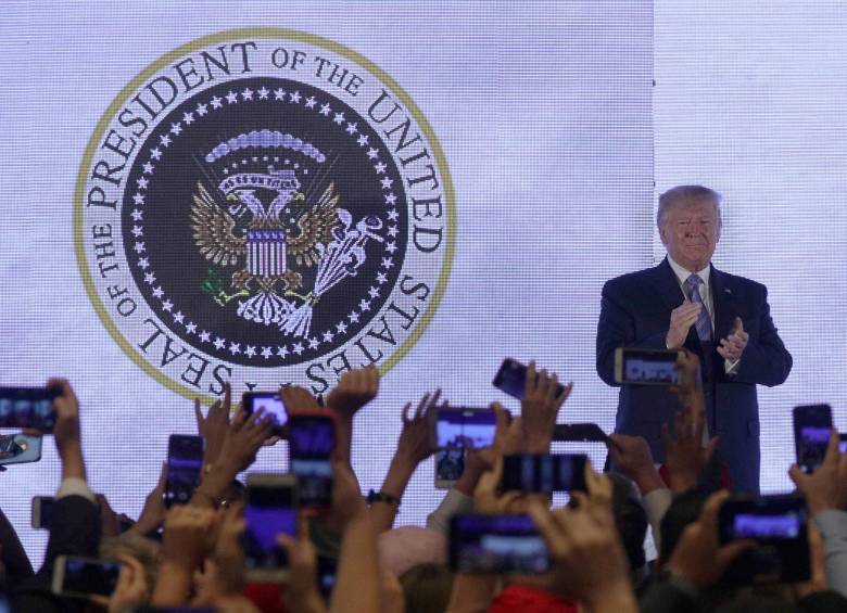 Al fondo puede verse el escudo de Estados Unidos alterado, con dos cabezas de ágila y palos de golf. FOTO: AFP
